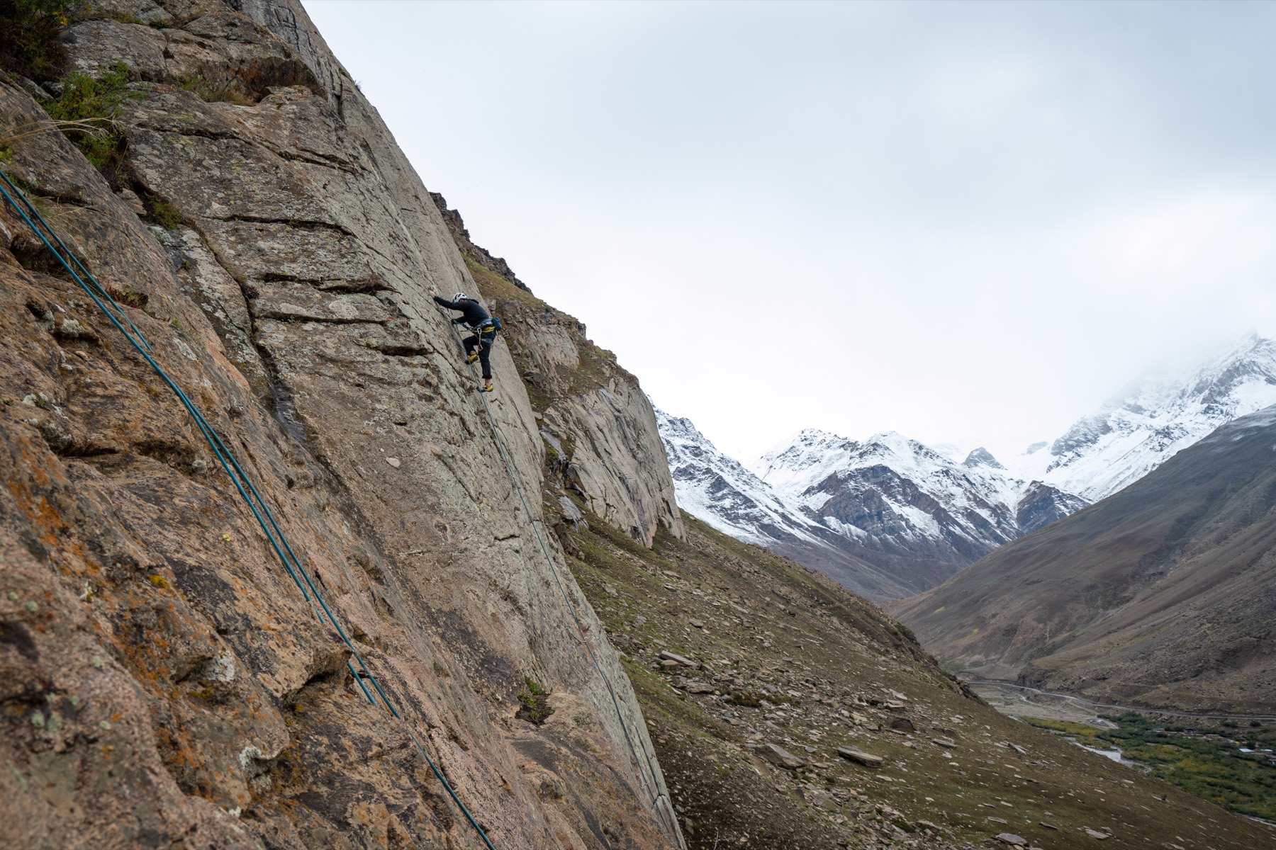 Climbing a big wall below snow peaks